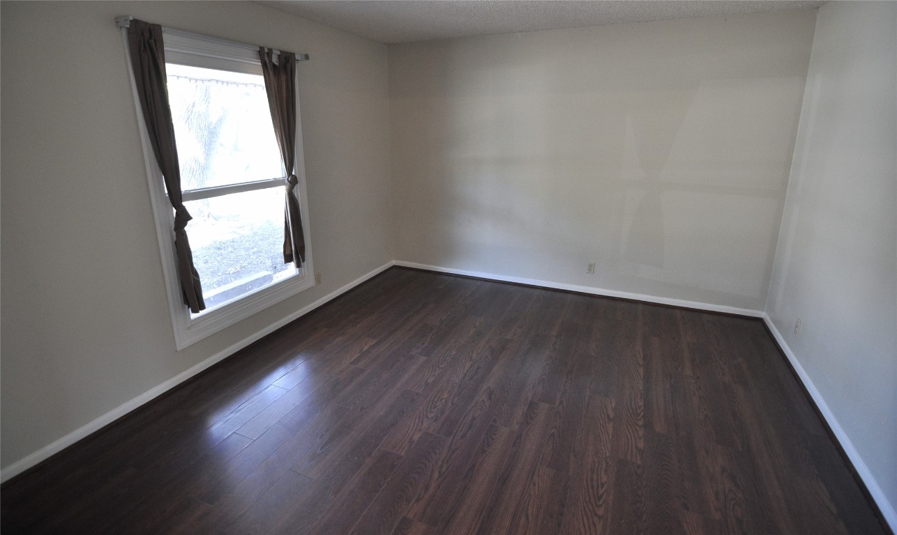 13203 Stillforest Street Austin, TX 78729 - Photo 2 of 24 Unfurnished room with dark wood finished floors and a textured ceiling