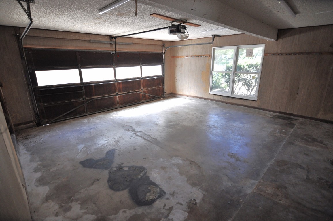 13203 Stillforest Street Austin, TX 78729 - Photo 10 of 24 Garage with wooden walls and a garage door opener