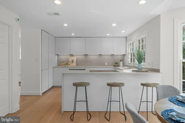 a kitchen with stainless steel appliances granite countertop a table chairs sink and cabinets