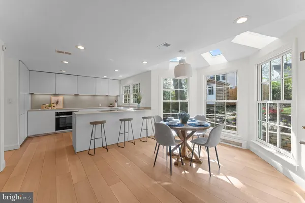 a kitchen with a table chairs wooden floors and white stainless steel appliances
