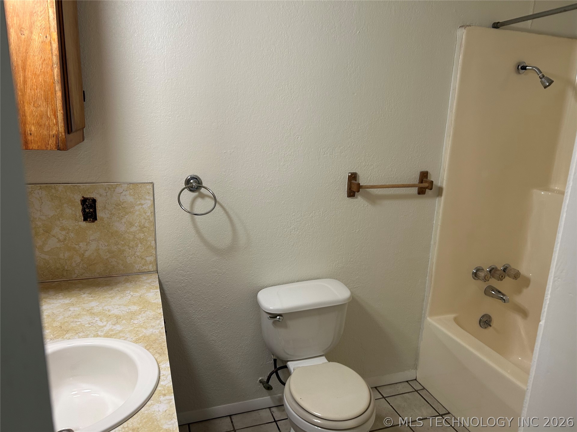 110955 East 1110 Road Sallisaw, OK 74955 - Photo 11 of 22 Bathroom featuring a white toilet, integrated sink with patterned countertop, wood-finish wall cabinet, and a shower-over-tub combination with chrome fixtures
