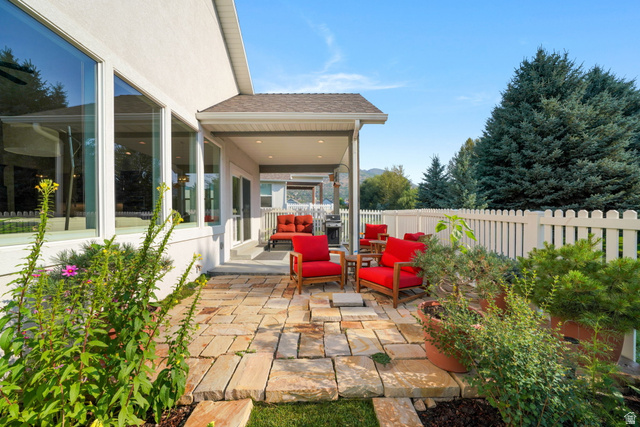 1238 Canyon View Road Midway, UT 84049 - Photo 27 of 33 Outdoor stone patio featuring a covered porch, white picket fencing, and mature evergreen landscaping