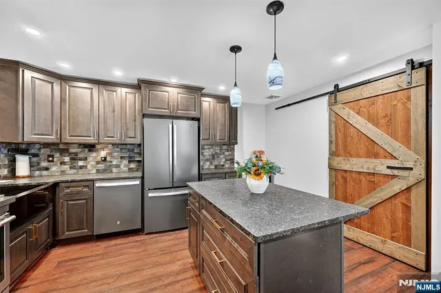 a kitchen with granite countertop stainless steel appliances and wooden floor