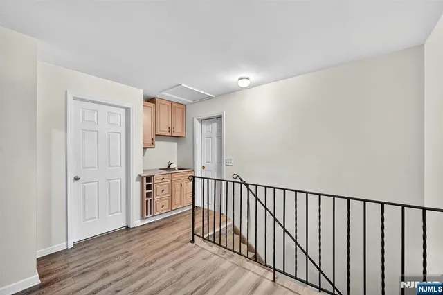 a view of a hallway with wooden floor and a bathroom
