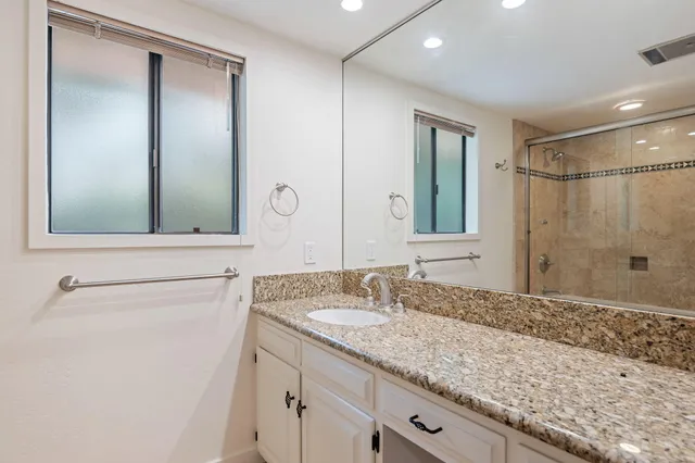 a bathroom with a granite countertop sink and a mirror