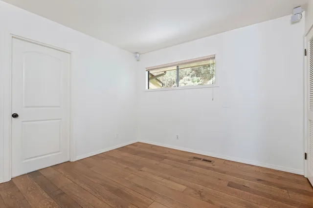 a view of an empty room with wooden floor and closet