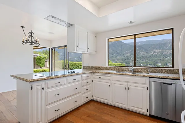 a kitchen with white cabinets and a large window