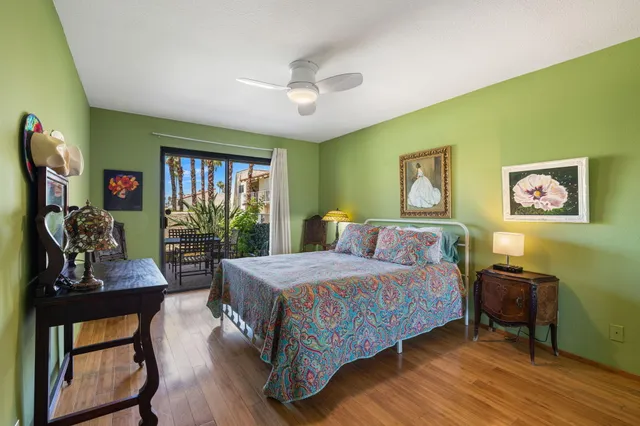a bedroom with a bed a dresser and potted plants with wooden floor