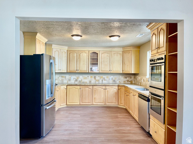 255 West Main Street Mount Pleasant, UT 84647 - Photo 3 of 35 Kitchen featuring extensive light wood cabinetry, stone-finish countertops, tile backsplash, stainless steel appliances, and wood-finish flooring