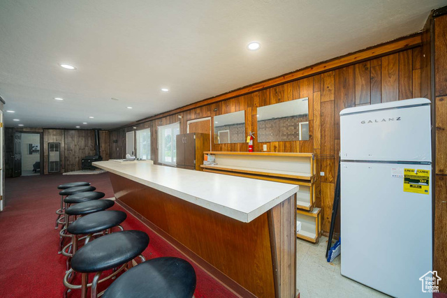 52 South Main Street Paris, ID 83261 - Photo 22 of 27 Kitchen featuring freestanding refrigerator, wood walls, light countertops, a breakfast bar, and recessed lighting