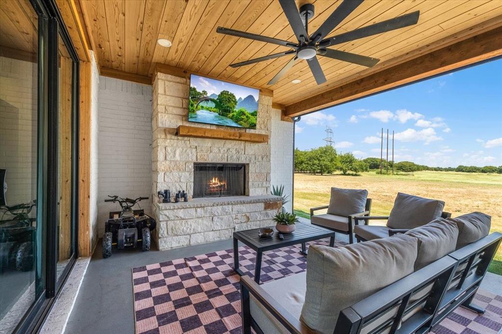 6080 Cates Rnch Drive Godley, TX 76044 - Photo 37 of 40 Covered patio with a wood-finish ceiling, stone fireplace, and a ceiling fan
