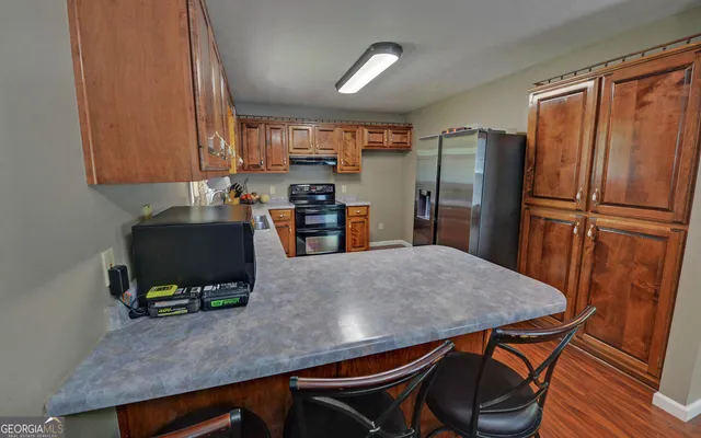 a kitchen with stainless steel appliances a refrigerator a stove a sink a dining table and chairs