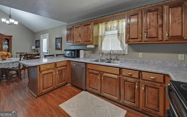 a kitchen with stainless steel appliances granite countertop wooden cabinets a sink and dishwasher with wooden floor