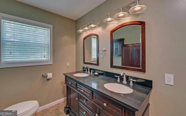 a bathroom with a granite countertop sink a toilet and a mirror