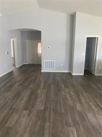 a view of an empty room with wooden floor and closet