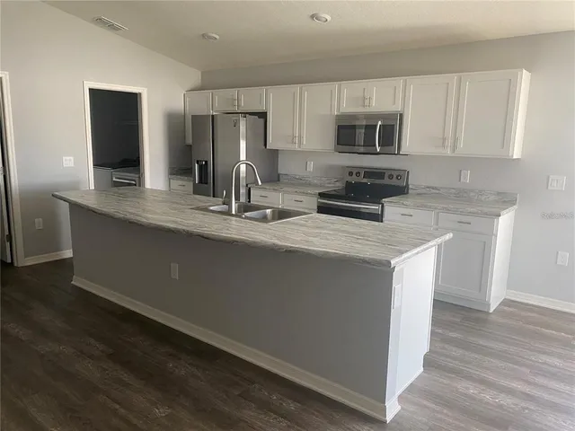 a kitchen with kitchen island granite countertop a sink stove and microwave
