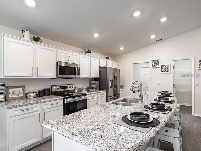 a kitchen with stainless steel appliances kitchen island granite countertop a sink stove and refrigerator