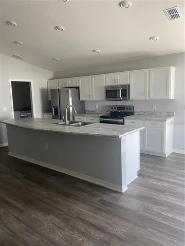 a kitchen with stainless steel appliances granite countertop a stove a sink and a microwave