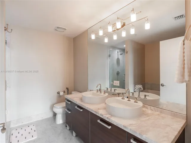 a bathroom with a granite countertop sink a large mirror and a toilet