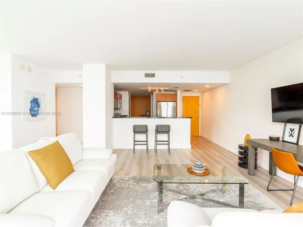 a living room with furniture a flat screen tv and kitchen view