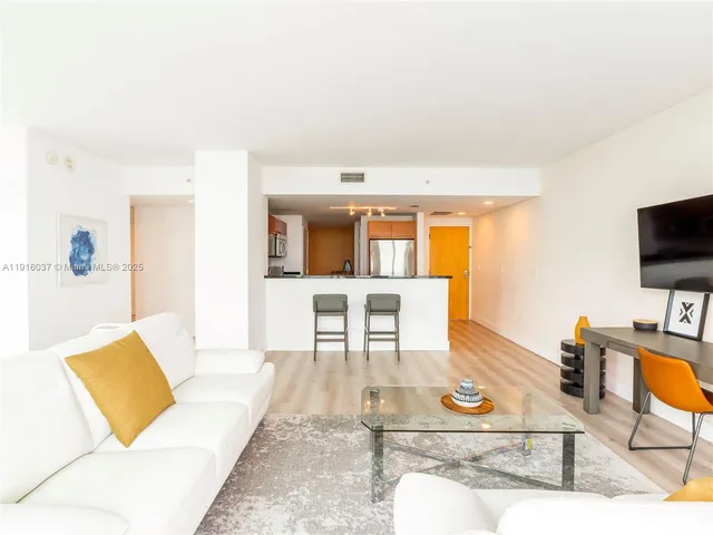 a living room with furniture a flat screen tv and kitchen view