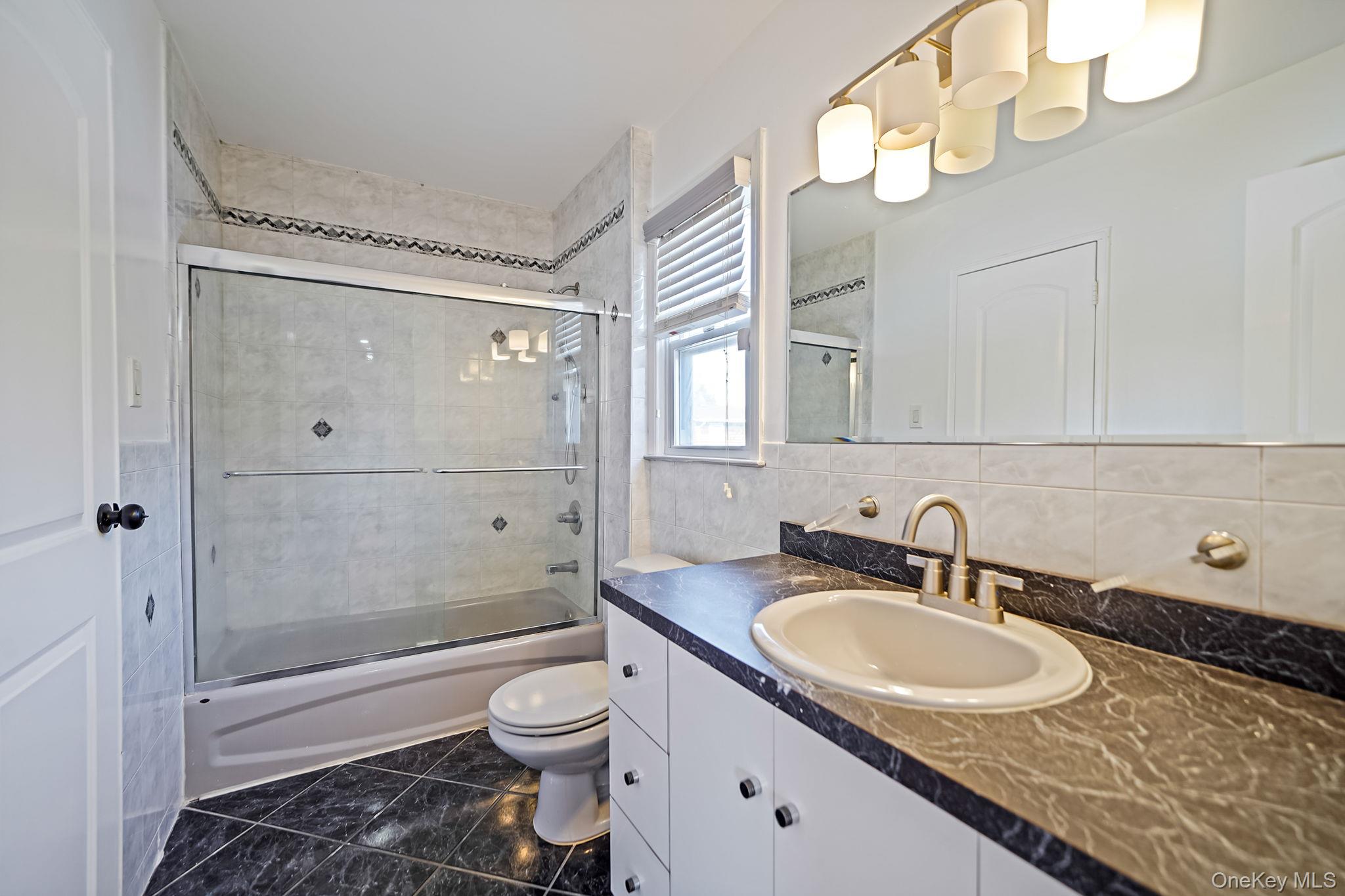 2415 Babylon Turnpike Merrick, NY 11566 - Photo 14 of 32 a bathroom with a granite countertop sink a toilet and shower