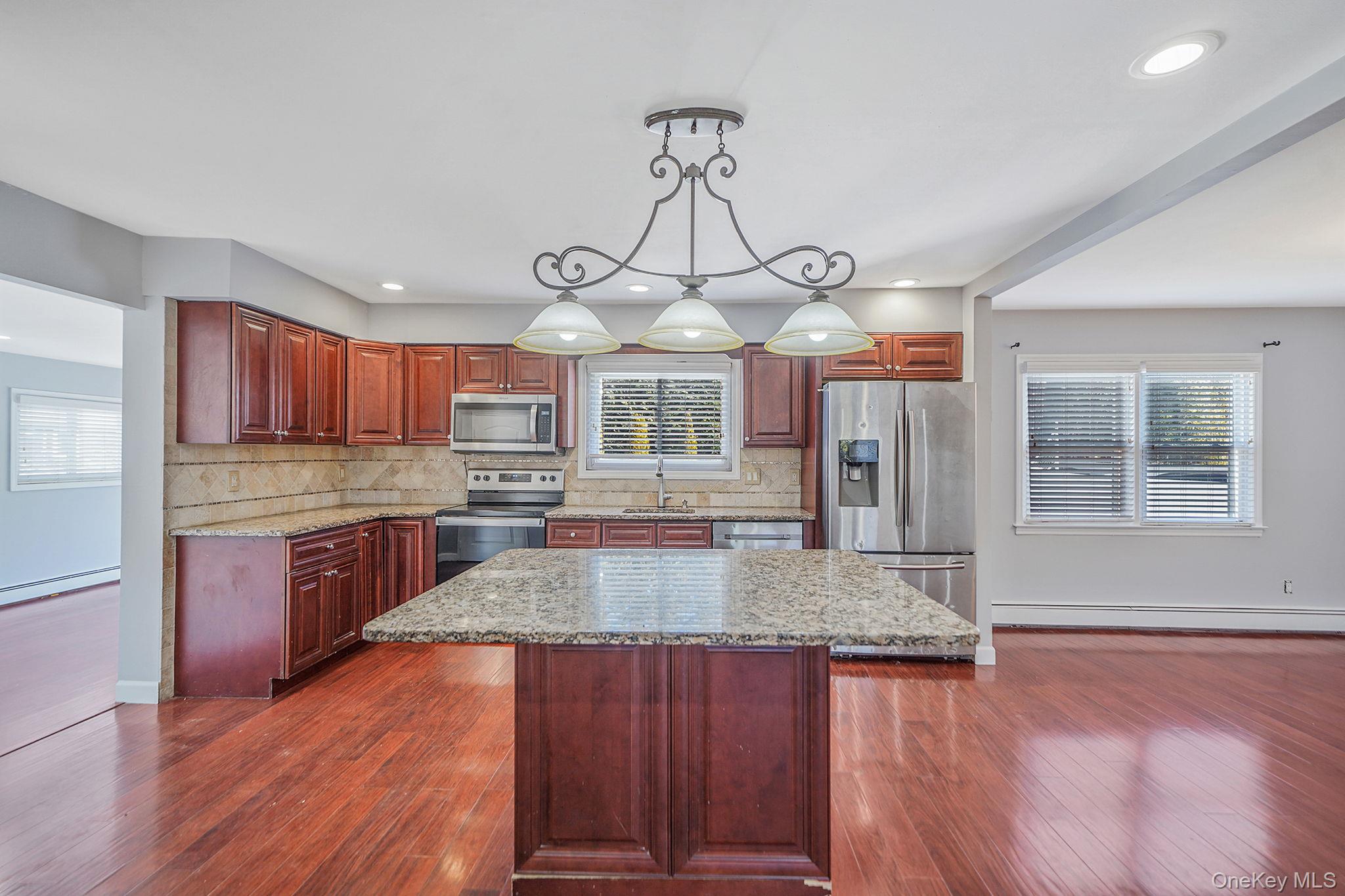 2415 Babylon Turnpike Merrick, NY 11566 - Photo 9 of 32 a large kitchen with kitchen island granite countertop wooden floors and wide window