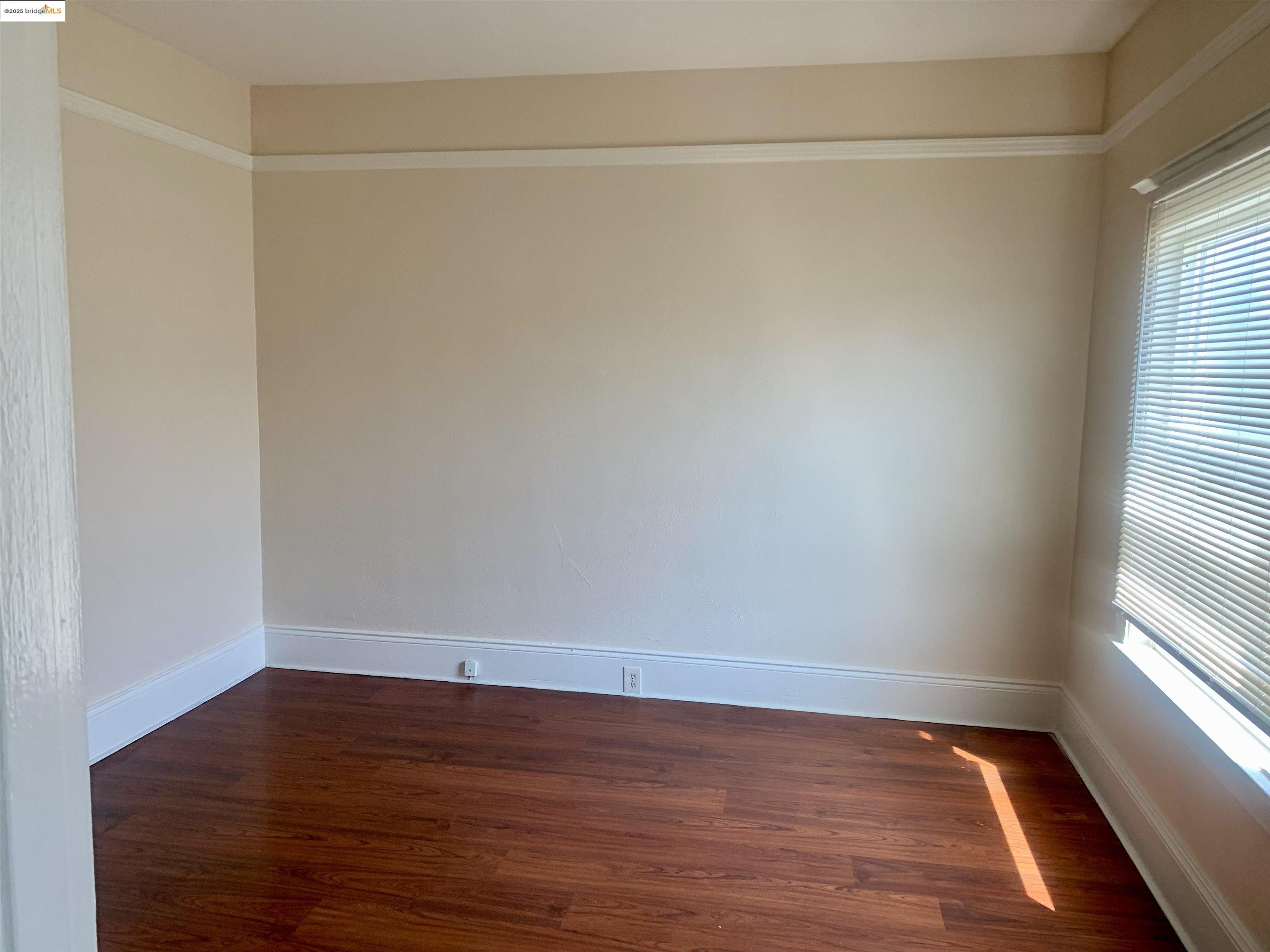 1028 61st Street Oakland, CA 94608 - Photo 13 of 28 a view of an empty room with wooden floor and a window