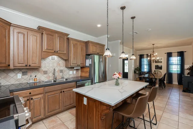 a kitchen with stainless steel appliances kitchen island granite countertop a table chairs and a refrigerator