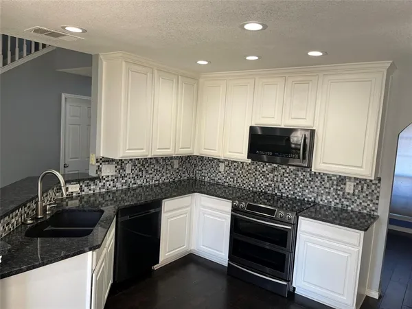a kitchen with granite countertop white cabinets and stainless steel appliances
