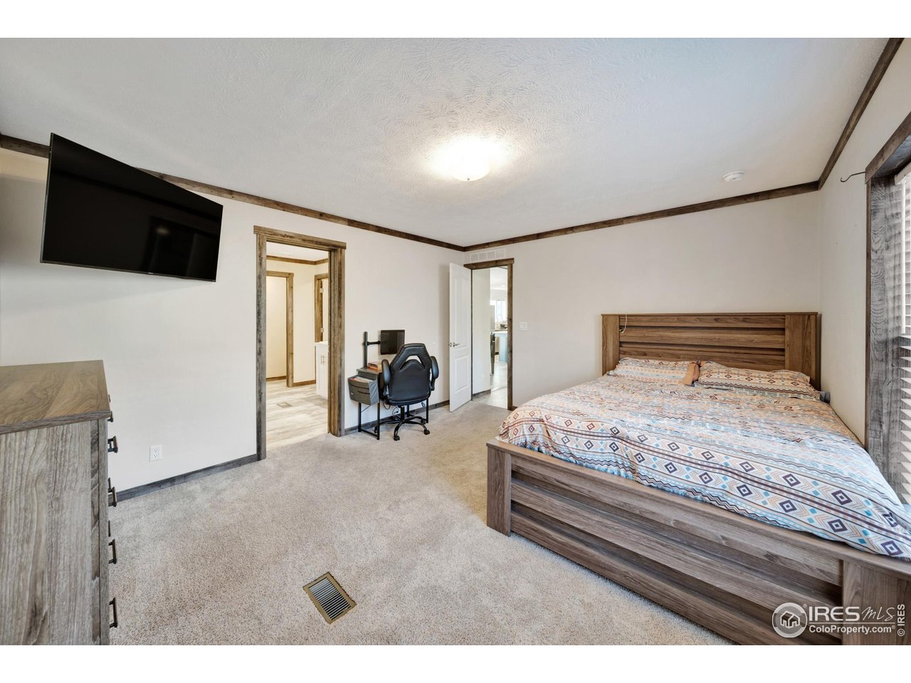 116 Ash Street Log Lane Village, CO 80705 - Photo 12 of 21 a bedroom with a bed a mirror on dresser and a flat screen tv