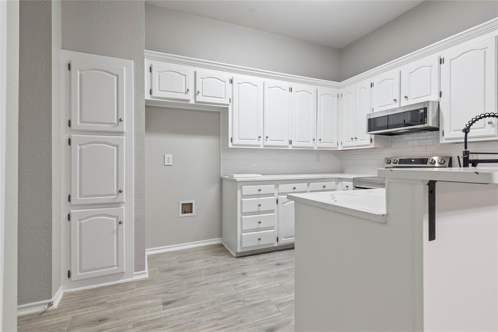304 Moore Creek Road, Unit 300 Hurst, TX 76053 - Photo 6 of 17 Kitchen featuring wood-finish flooring, white cabinetry, integrated stainless steel appliances, and solid surface countertops