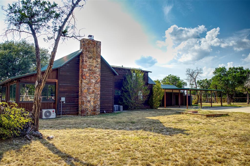 2525 Dodson Pr Road Gordon, TX 76453 - Photo 16 of 31 View of home's exterior featuring a chimney, a yard, a metal roof, and a carport
