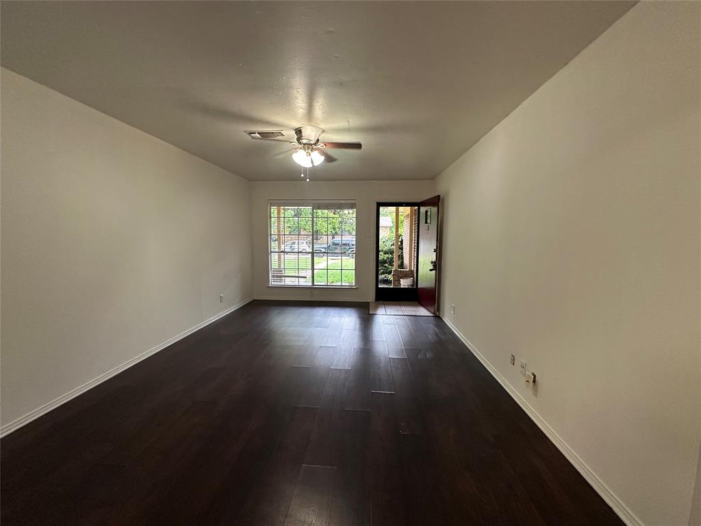 2109 Quail Run, Unit A McKinney, TX 75071 - Photo 4 of 16 an empty room with wooden floor and windows