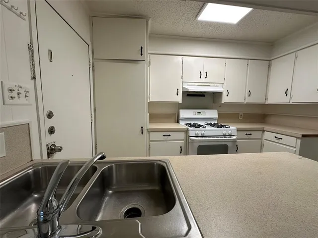 a kitchen with stainless steel appliances a stove a sink and white cabinets