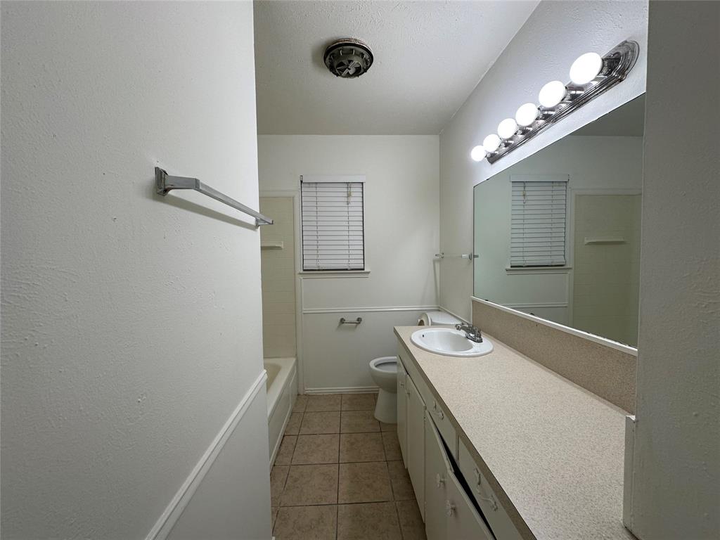 2109 Quail Run, Unit A McKinney, TX 75071 - Photo 10 of 16 a bathroom with a granite countertop sink a toilet and a mirror