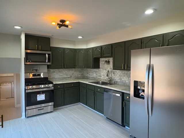 a kitchen with stainless steel appliances granite countertop a refrigerator and a stove top oven