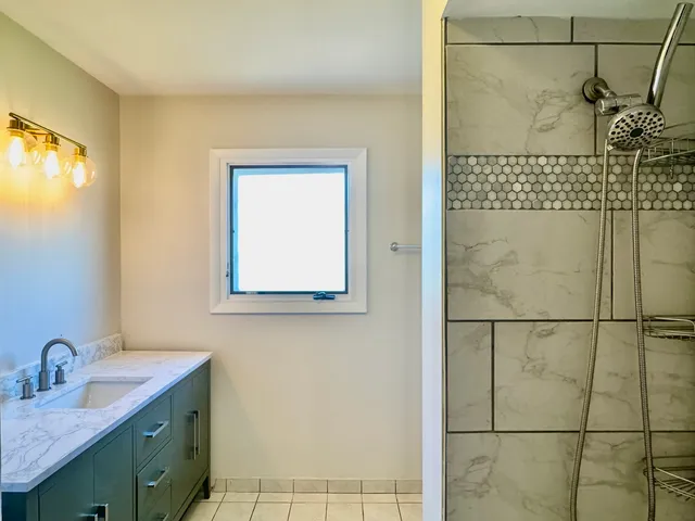 a bathroom with a granite countertop sink a mirror and shower