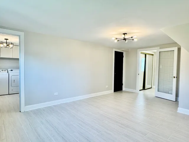 a view of a big room with wooden floor and a chandelier fan