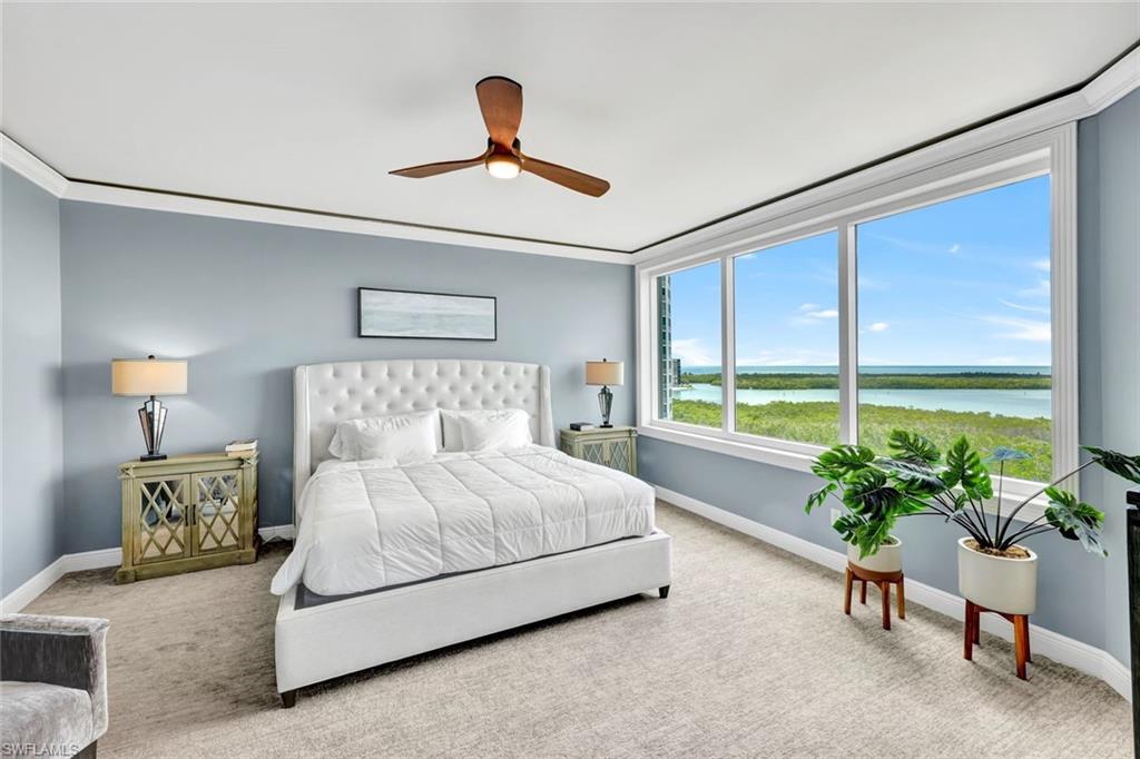275 Indies Way, Unit 902 Naples, FL 34110 - Photo 12 of 39 a bedroom with a large bed and a potted plant
