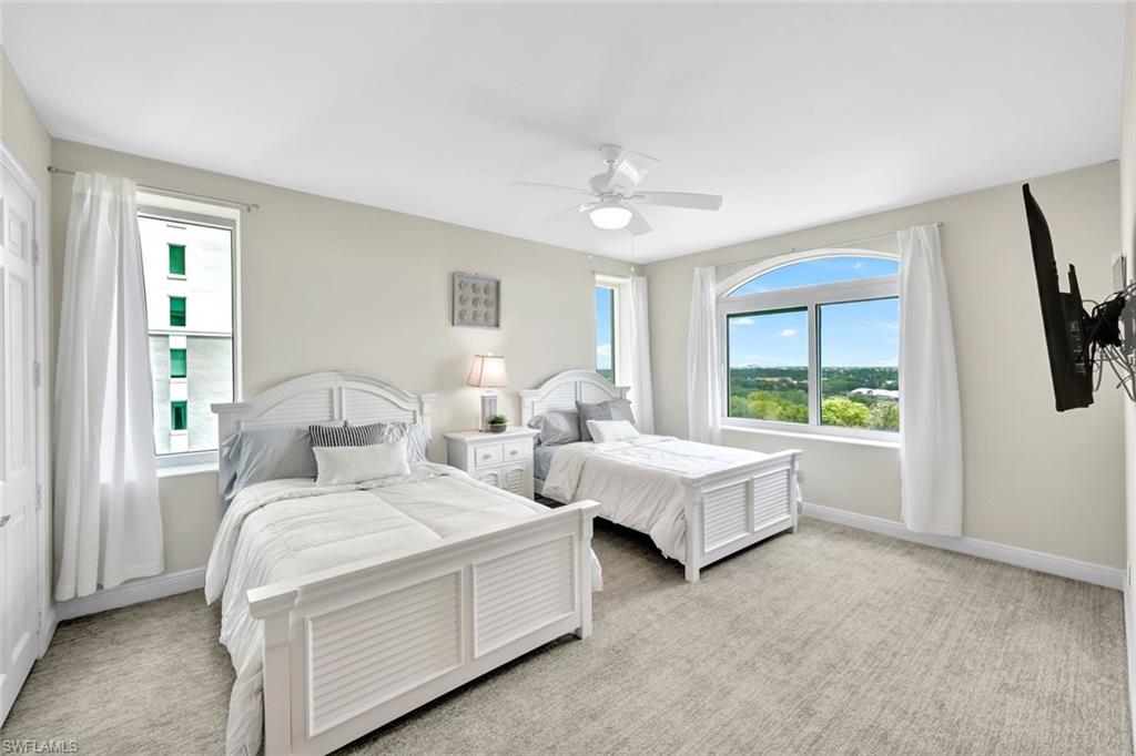 275 Indies Way, Unit 902 Naples, FL 34110 - Photo 18 of 39 a bedroom with bed a flat tv screen and a large window with the outer view
