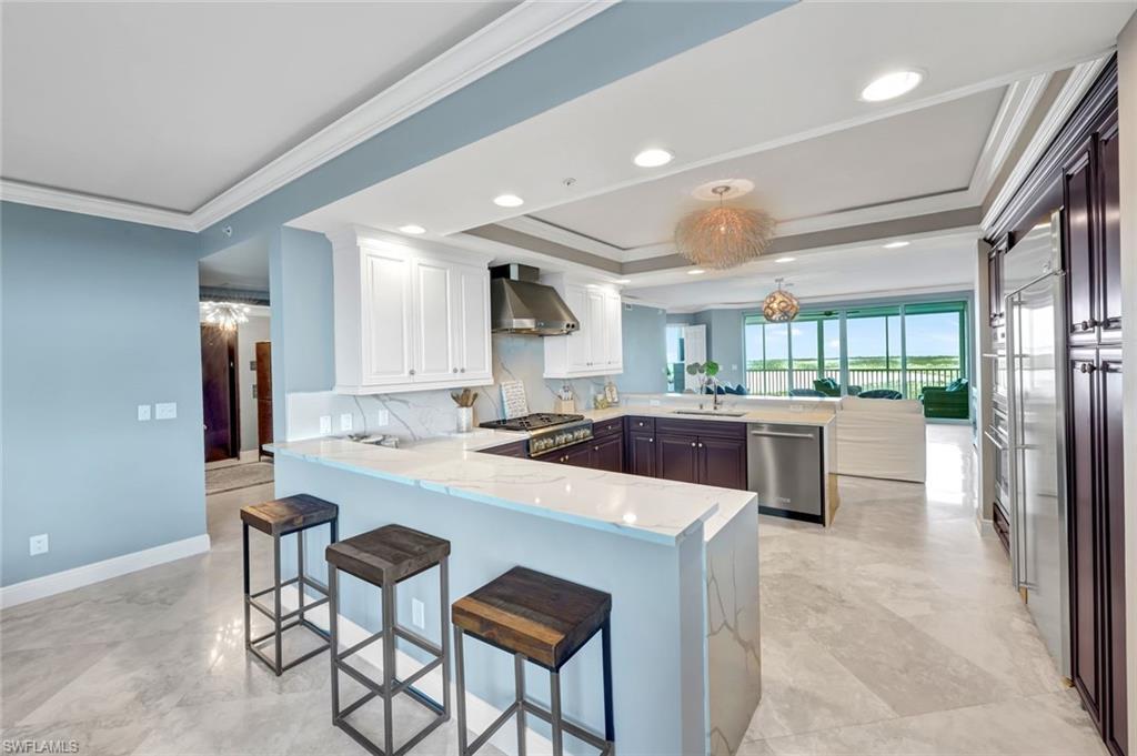 275 Indies Way, Unit 902 Naples, FL 34110 - Photo 8 of 39 a kitchen with a sink a refrigerator and chairs