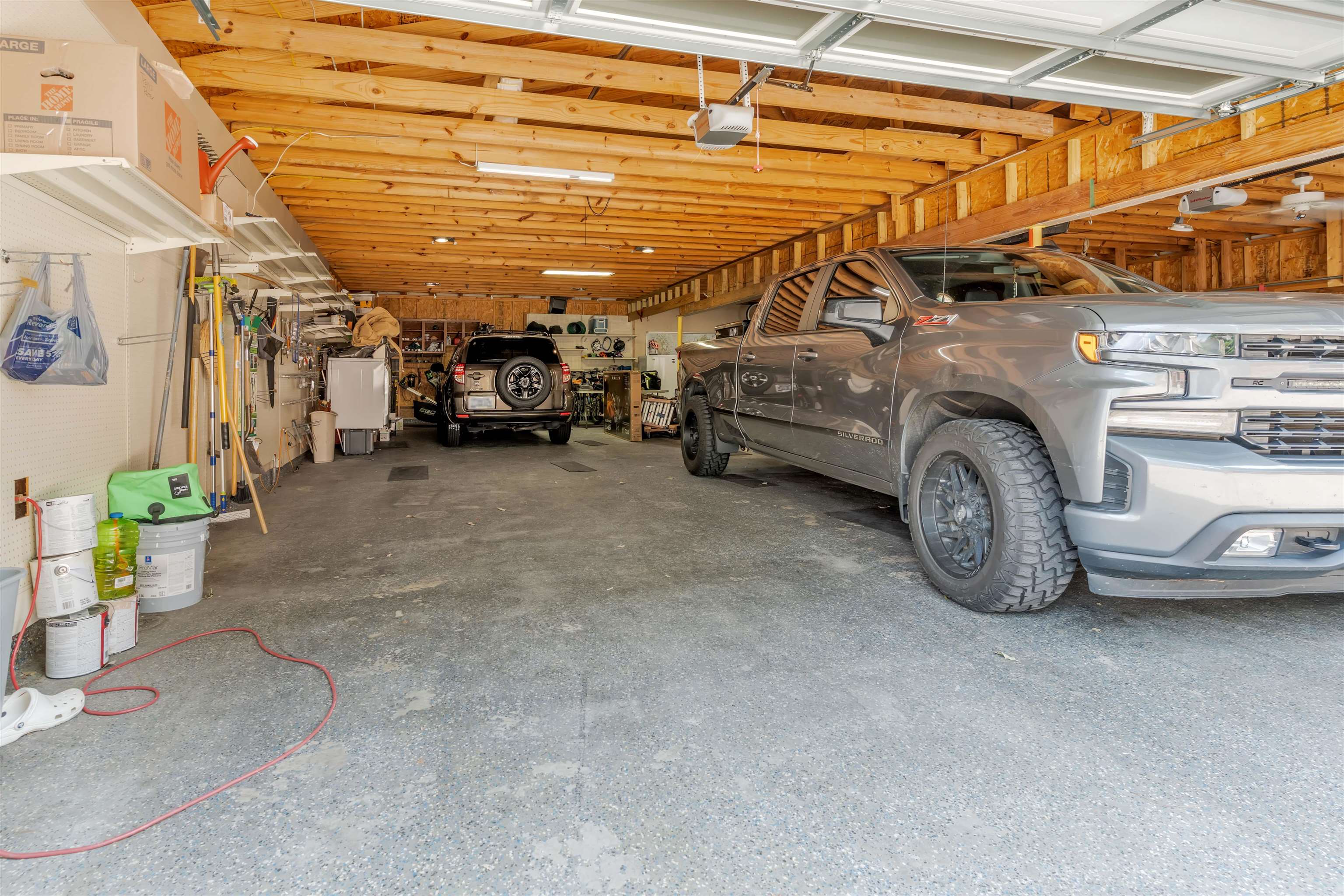 5187 South Angela Road Memphis, TN 38117 - Photo 34 of 39 Spacious three-car garage featuring exposed wood beam ceiling, concrete flooring, and multiple overhead light fixtures