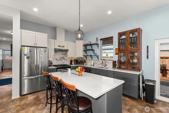 a kitchen with stainless steel appliances a refrigerator a stove a sink a dining table and chairs