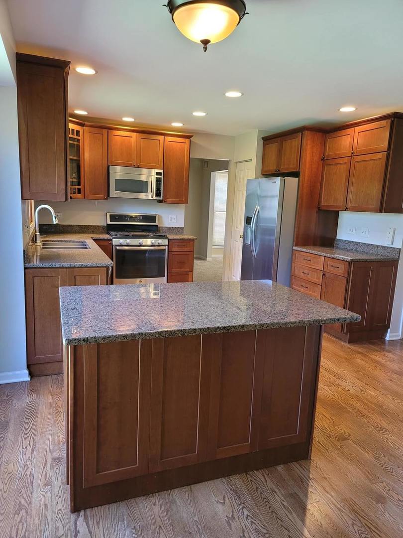 950 Ripple Brook Lane Elgin, IL 60120 - Photo 11 of 38 a kitchen with stainless steel appliances wooden cabinets a sink and a refrigerator
