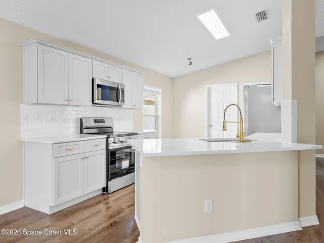 a kitchen with stainless steel appliances white cabinets a sink and a stove