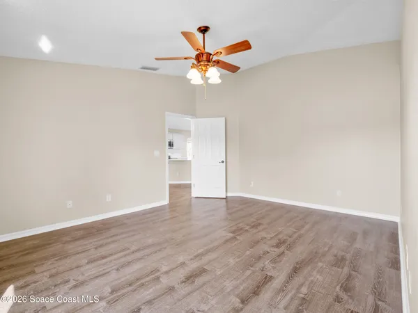 wooden floor in a room with a ceiling fan and window