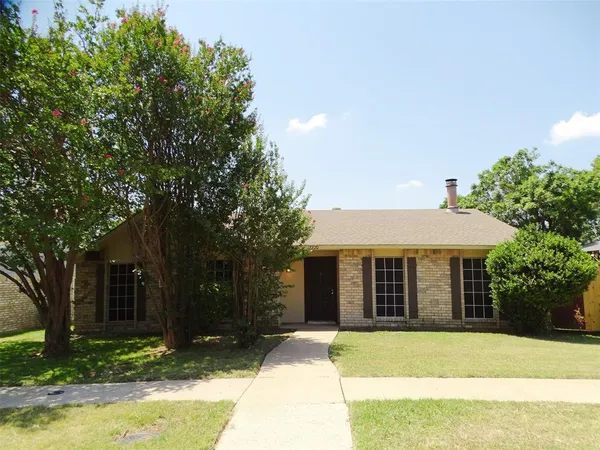 a front view of a house with a garden and trees