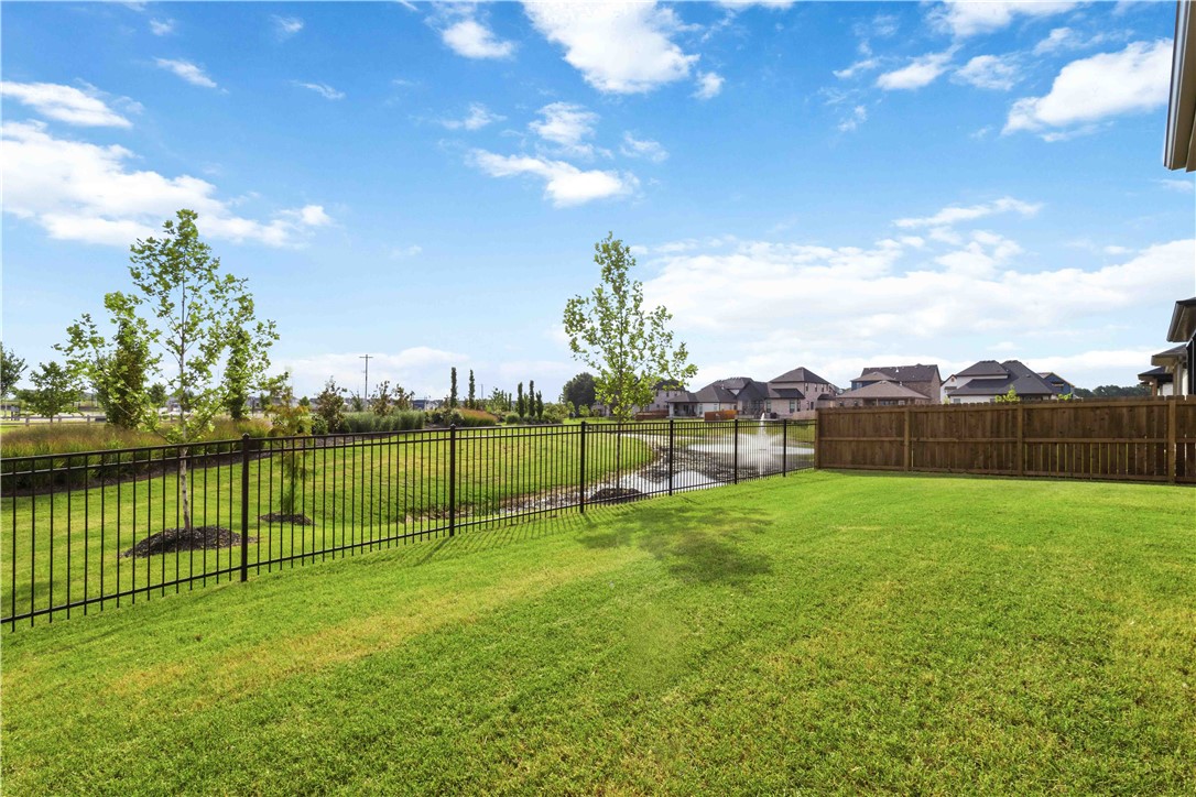 450 Fox Trail Springdale, AR 72762 - Photo 4 of 38 Expansive grassy lawn bordered by a black wrought iron fence and a wood privacy fence