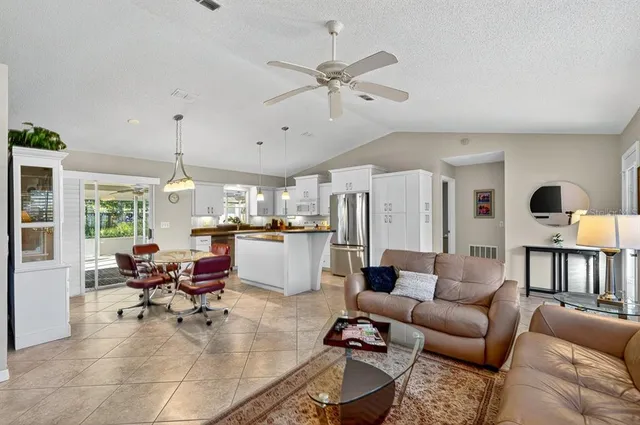 a kitchen with granite countertop a refrigerator a sink a stove and white cabinets